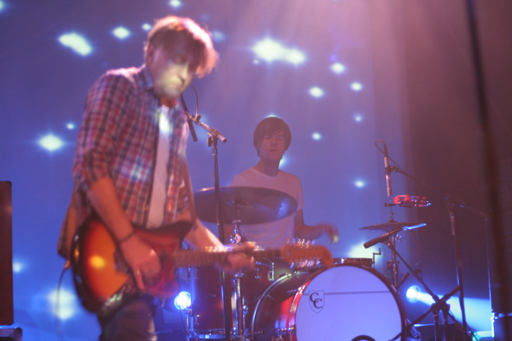 Drummer performing under stage lights during a live concert