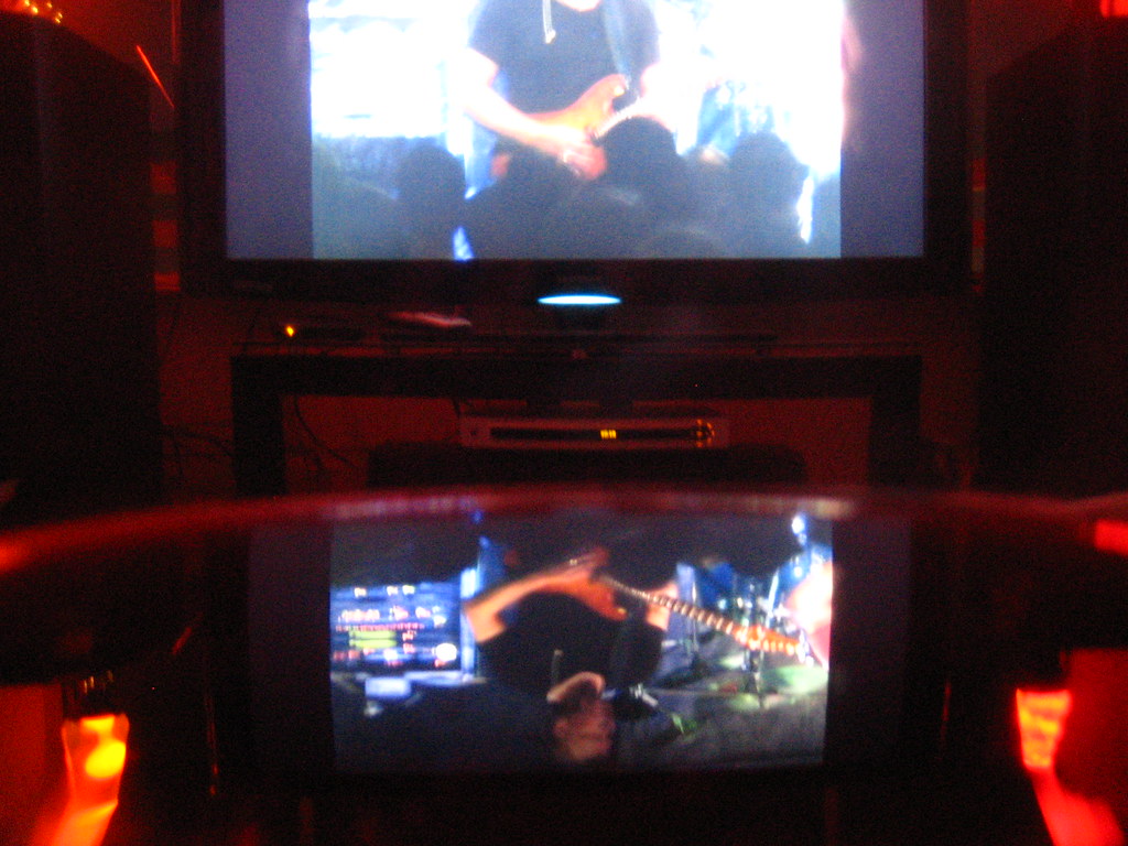 Watching and evaluating a live performance video on home screens with speakers nearby.